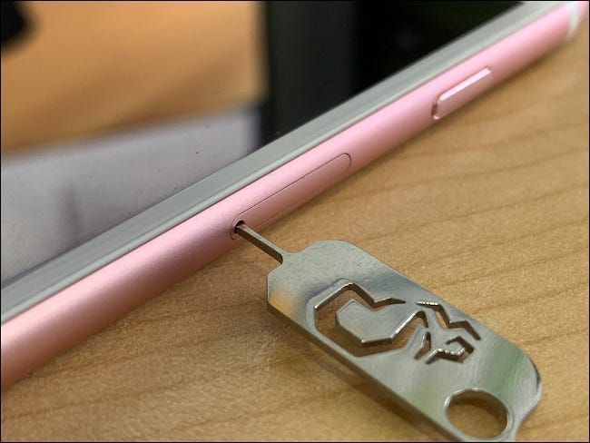 Una herramienta de extracción de tarjeta SIM insertada en el costado de un iPhone de Apple