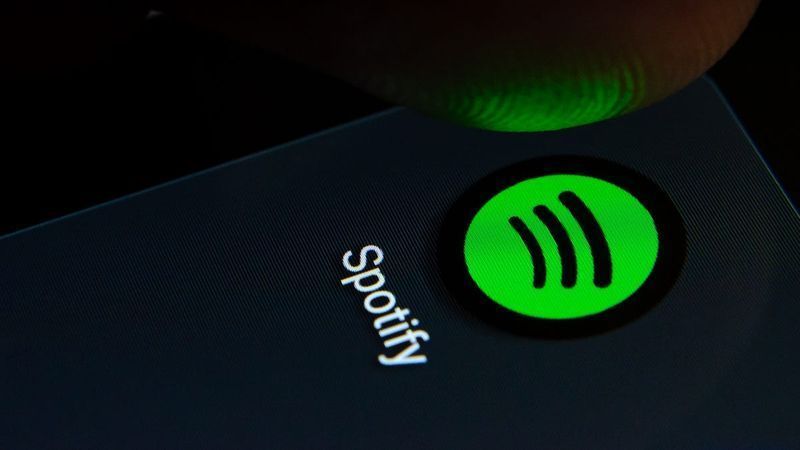 Person, die auf einem Smartphone auf das Logo der Spotify-App tippt