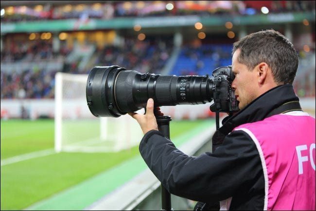 Un fotografo con un grande zoom ottico durante una partita di calcio.