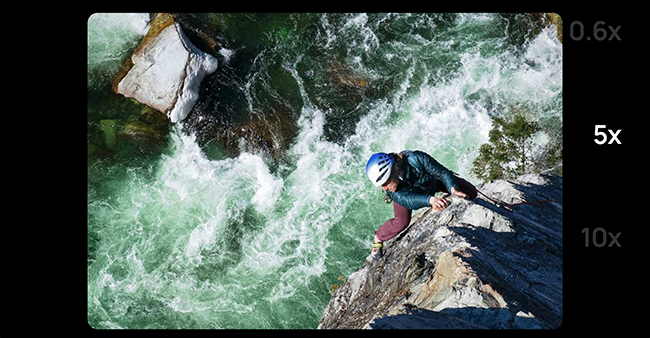 Zoom di un uomo su una corda che si arrampica sulle rocce vicino a un fiume impetuoso.