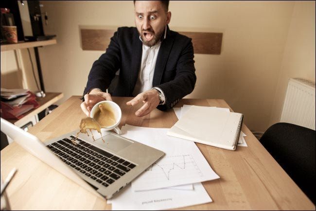 אדם ששופך קפה על מחשב נייד.