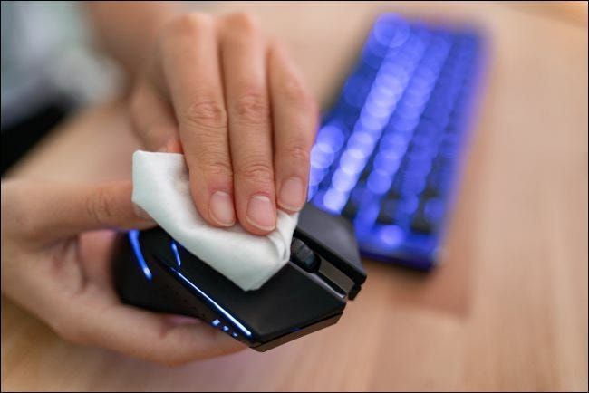 يد تمسح فأرة الكمبيوتر بقطعة قماش.