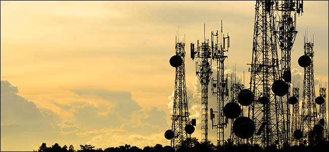 Un montón de torres de radiodifusión flanqueadas por una hermosa puesta de sol.