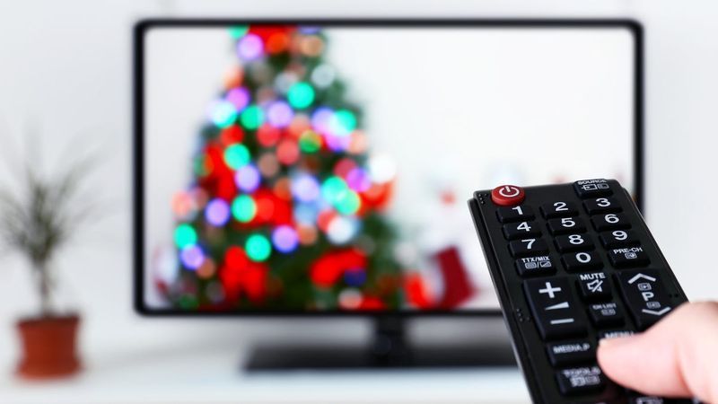 אדם מכוון שלט לכיוון טלוויזיה שמנגן סרט חג המולד