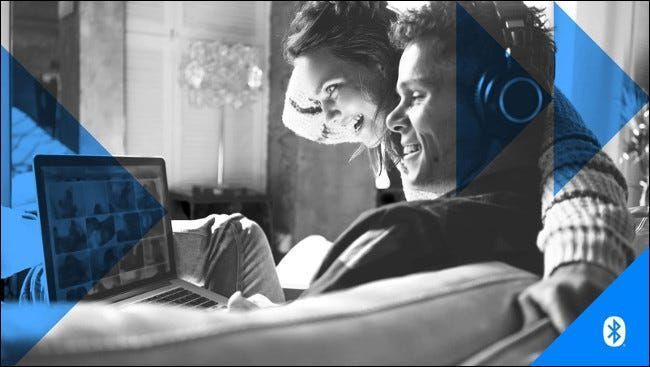 Seorang lelaki dan wanita memakai fon kepala sambil melihat skrin komputer riba.