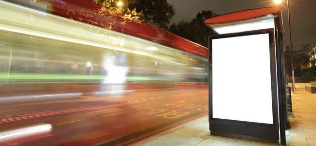 Prazen pano na avtobusni postaji ponoči z lučmi avtomobilov, ki gredo mimo odličnega prostora za kopiranje za vaš dizajn, posnet v Londonu, Združeno kraljestvo, Združeno kraljestvo