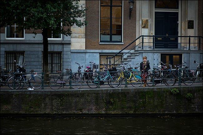 Eine Frau steht auf einer Brücke hinter einer Reihe abgestellter Fahrräder.
