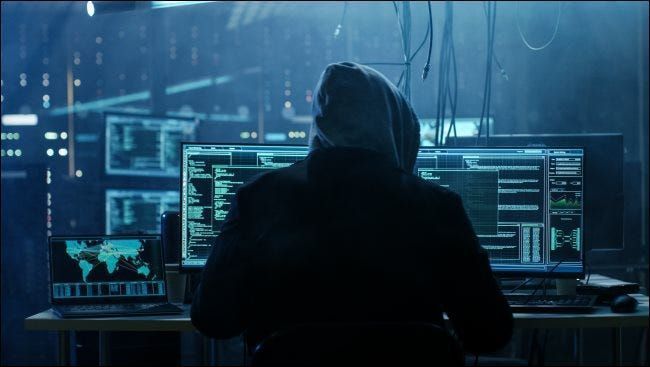 Сенчен хакер с качулка, седнал пред компютър.