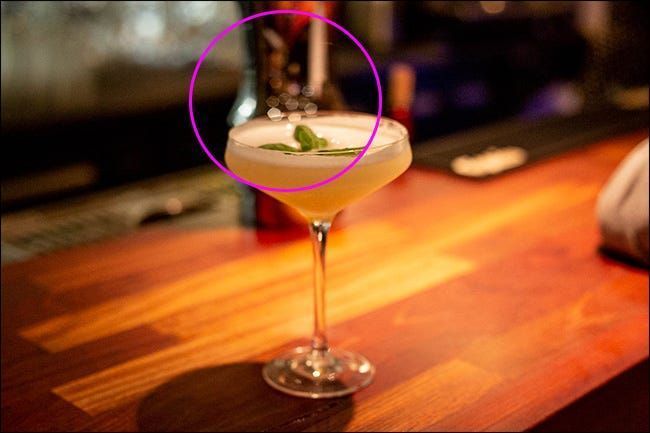 Et cocktailglass på en bar med polygonal bokeh i midten.