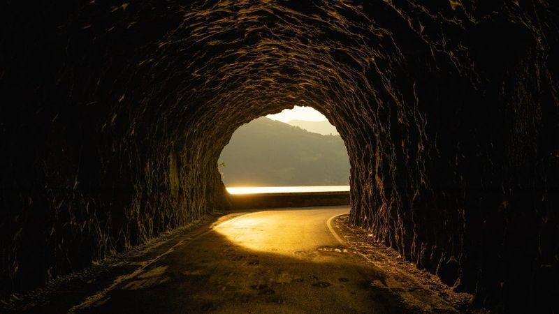 Камени тунел са заласком сунца на другој страни.
