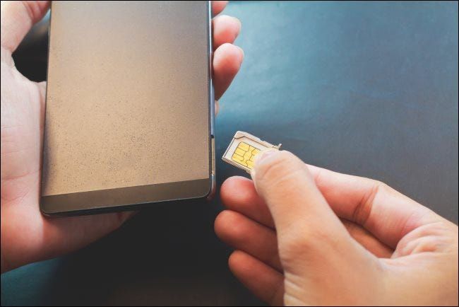 Eine Hand, die eine SIM-Karte in ein Smartphone einlegt.