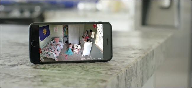 iPhone, kurā redzama Wyze Cam plūsma, kurā bērns spēlējas savā guļamistabā.
