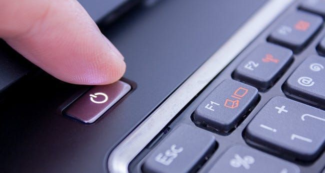 Ein Finger drückt einen Laptop-Netzschalter.