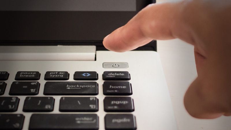 Ein Finger kurz davor, einen Laptop-Netzschalter zu drücken.