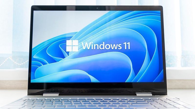 „Windows 11“ logotipas ir darbalaukio fonas nešiojamajame kompiuteryje.